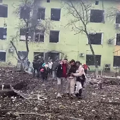 <strong>3. Prédio do hospital infantil e maternidade</strong> avariado ao fundo enquanto pacientes são socorridos.